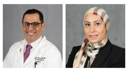 Two individuals in professional attire posed against a neutral gray background. 